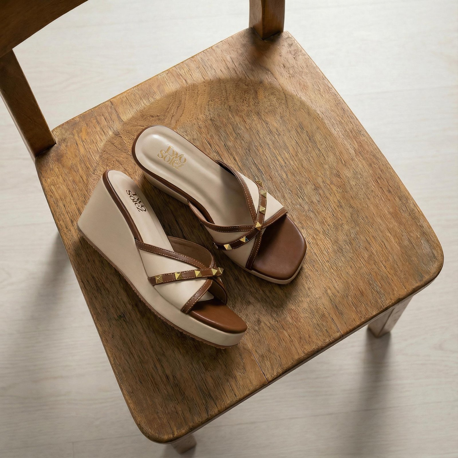 Nomad Bloom patterned wedge sandals worn by a seated model